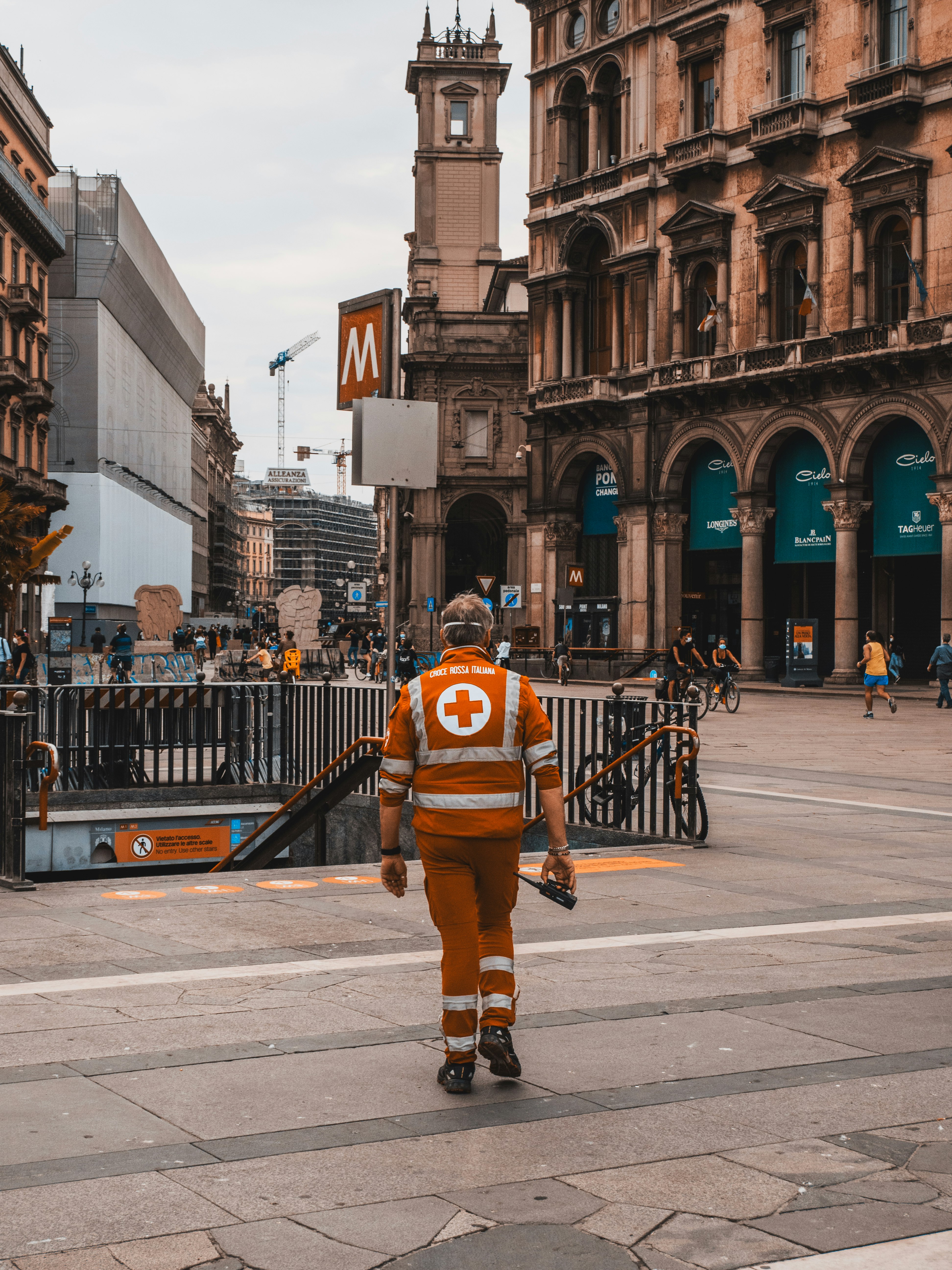 man in orange and black jacket walking on pedestrian lane during daytime